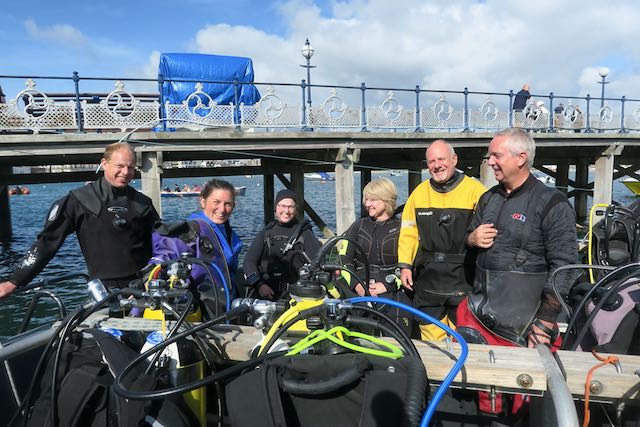 Six North West Kent Divers club members on a boat at Swanage Pier with diving equipment in the foreground